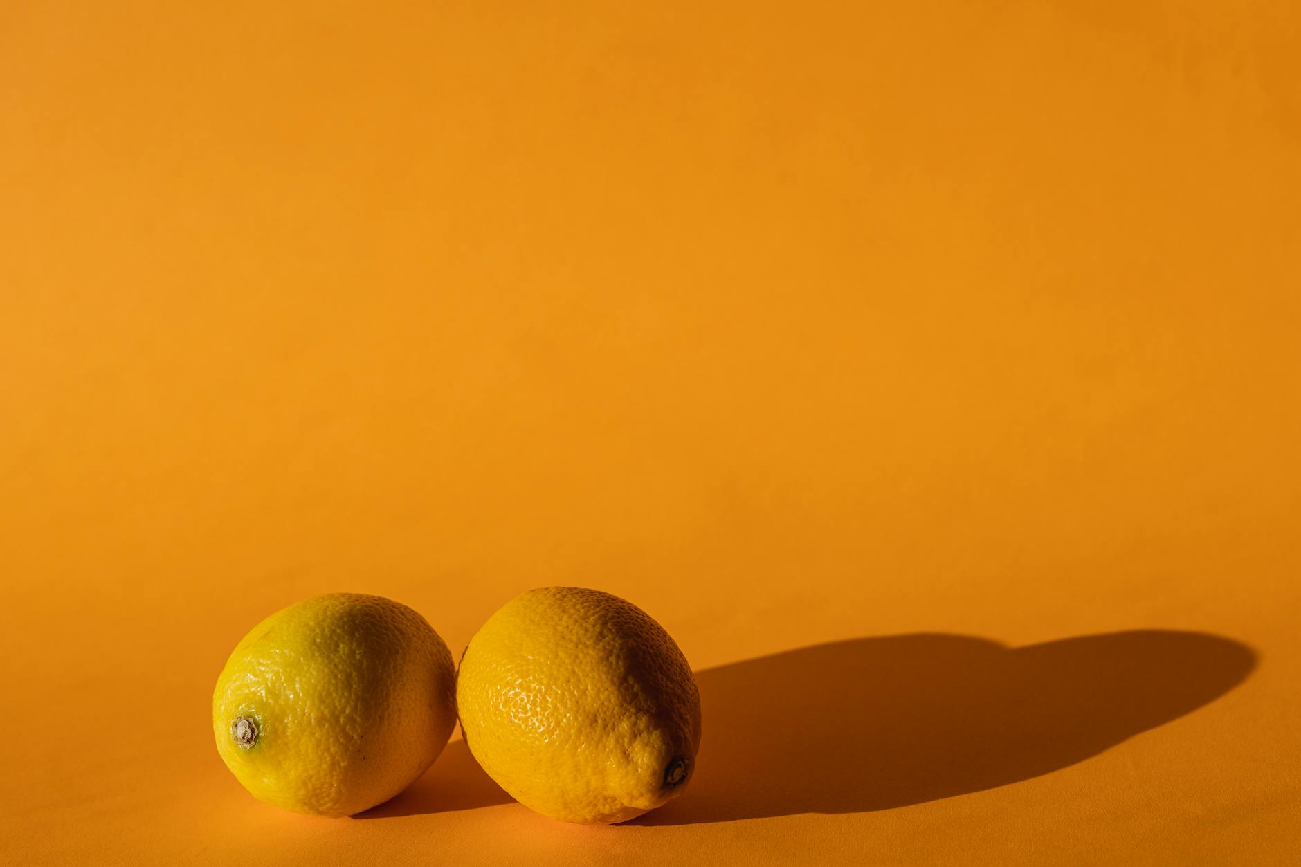 Bright yellow silicone vibrator surrounded by fresh fruit on yellow background, representing pleasure and sensation recovery